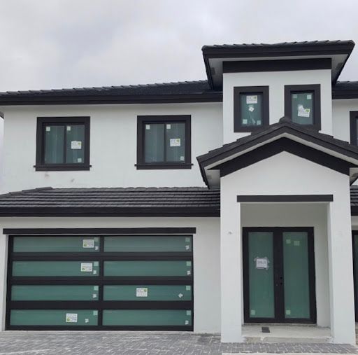 A white house with black trim and a green garage door.