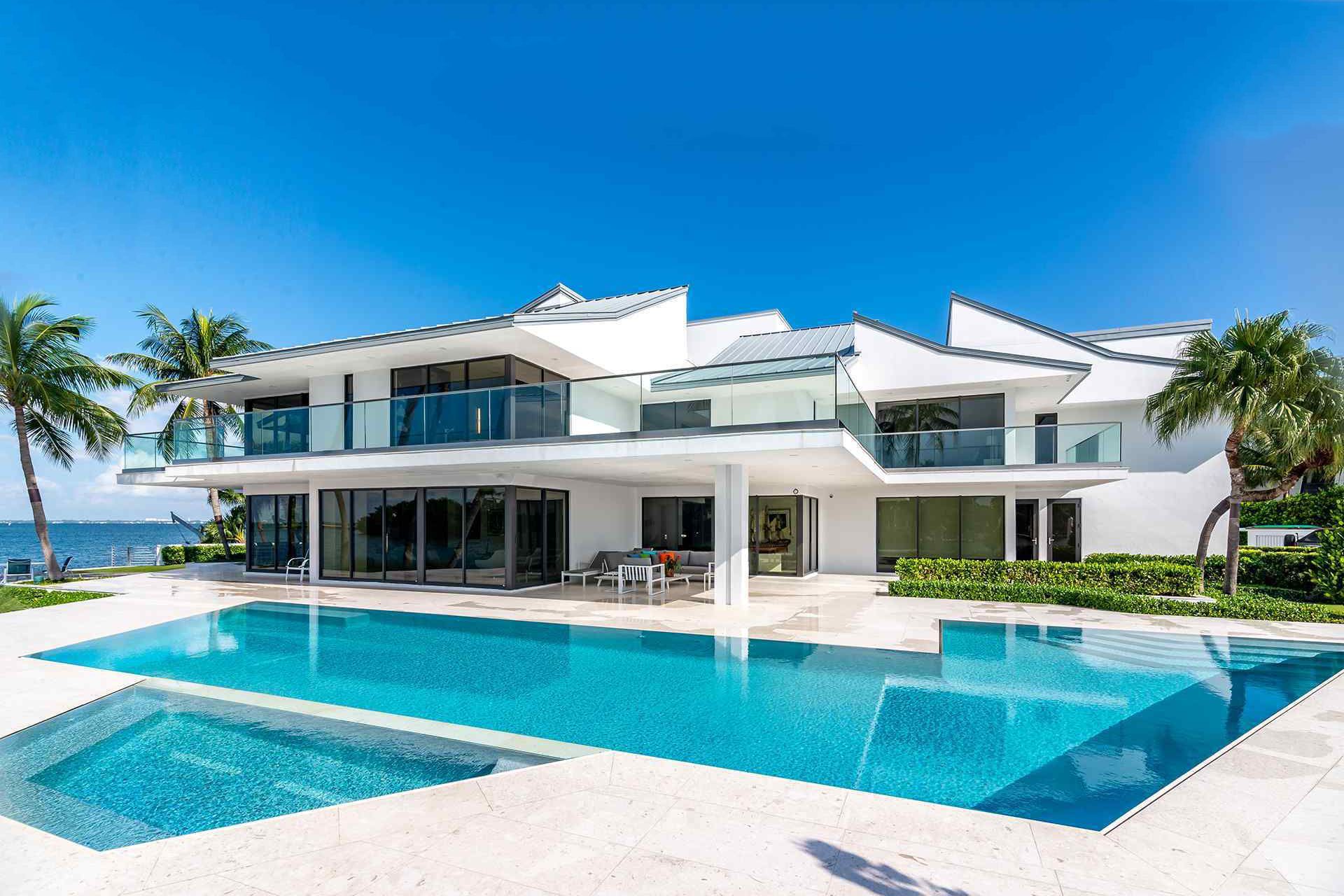 A large white house with a large swimming pool in front of it.