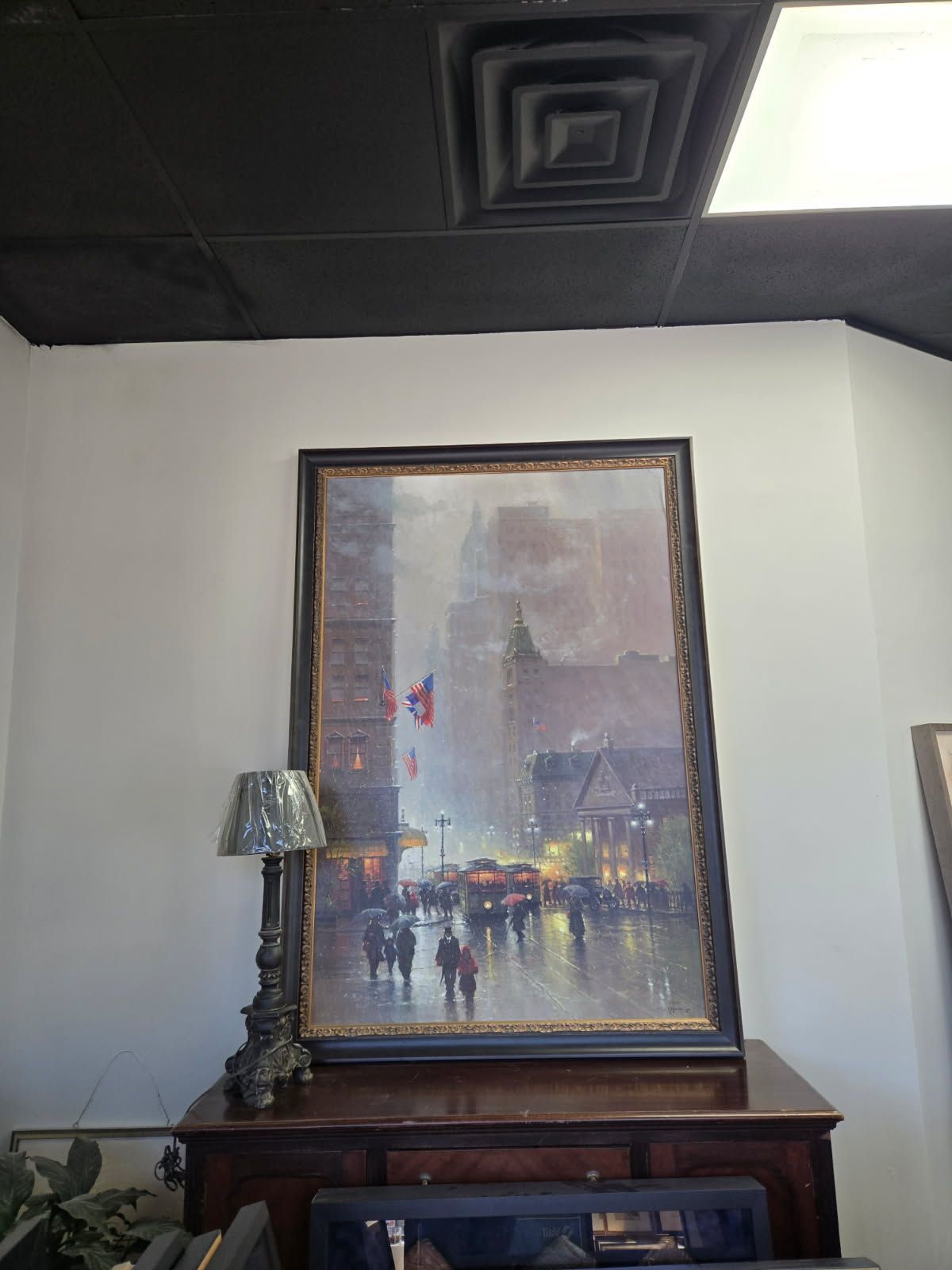 A large painting is hanging on a wall next to a lamp