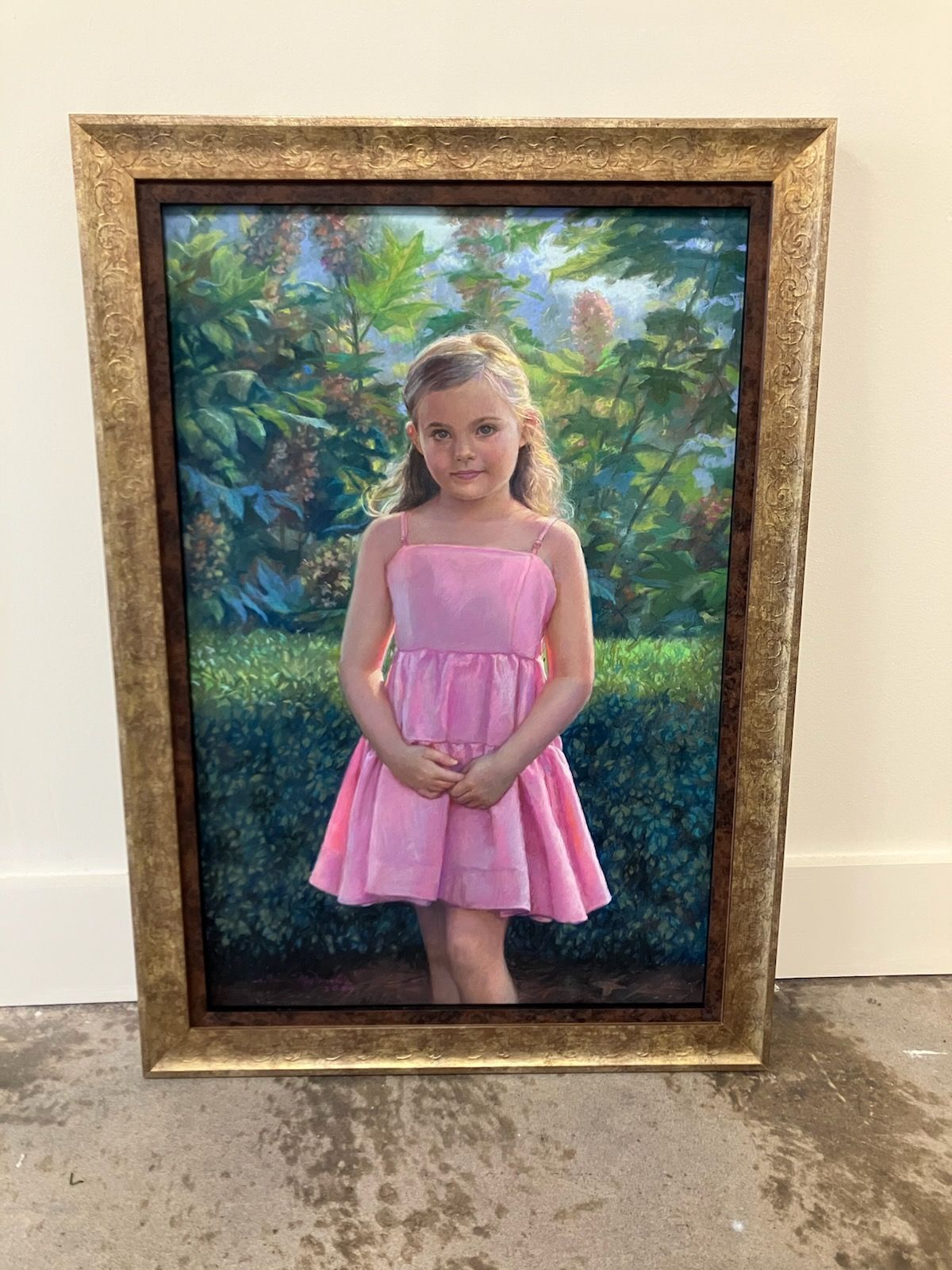 A framed painting of a little girl in a pink dress