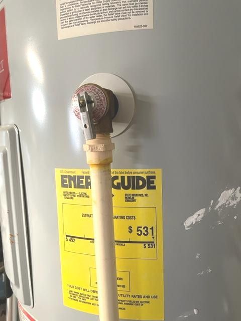Water heater with gas line and yellow EnergyGuide label in a utility room.