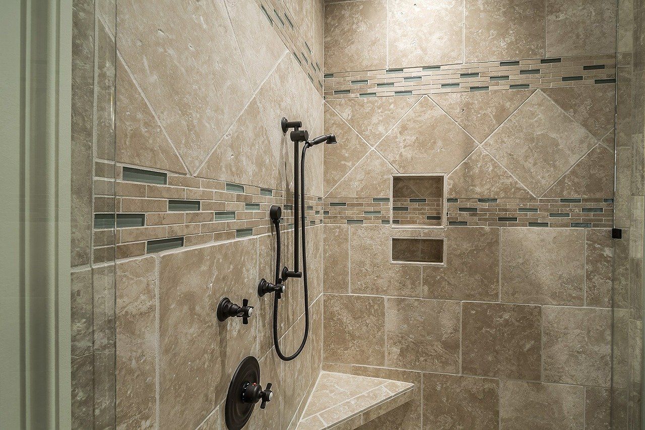 Stone-tiled shower with chrome fixtures and decorative accent tile band