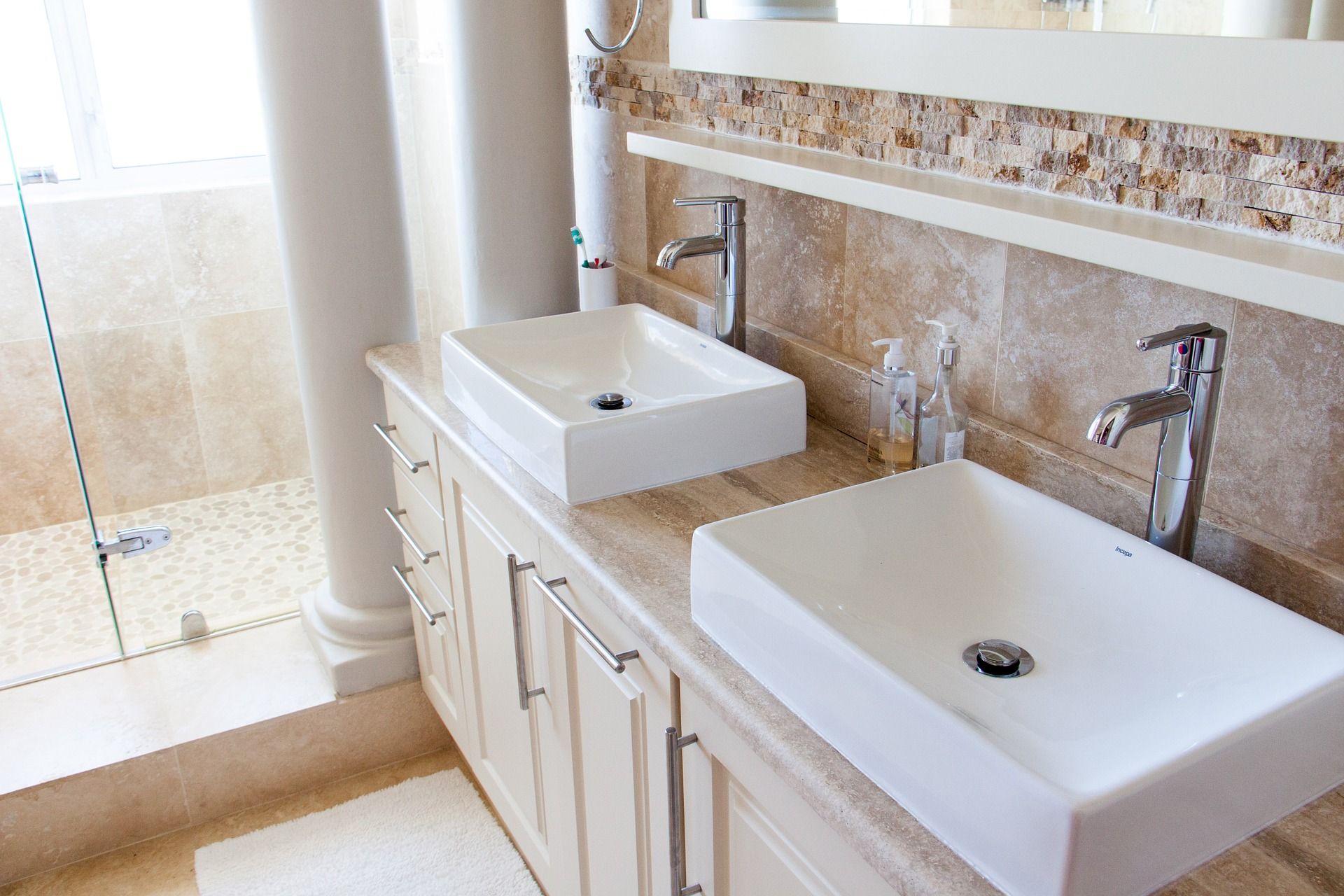 Modern bathroom with double rectangular sinks, chrome faucets, and beige marble countertops.