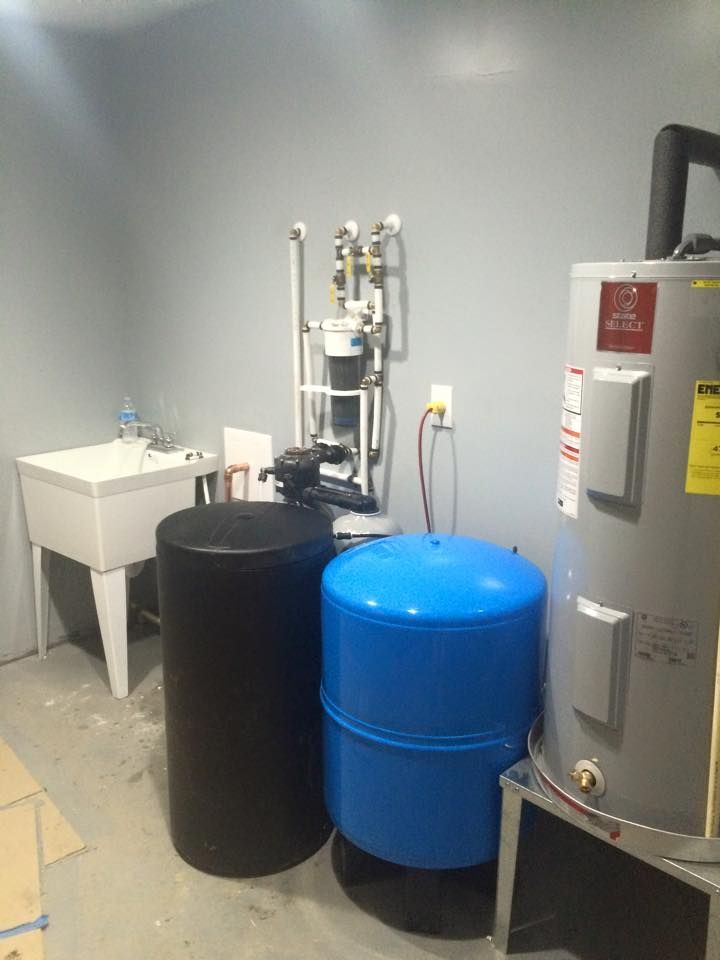 Industrial utility room with blue and black barrels beside a water heater and sink
