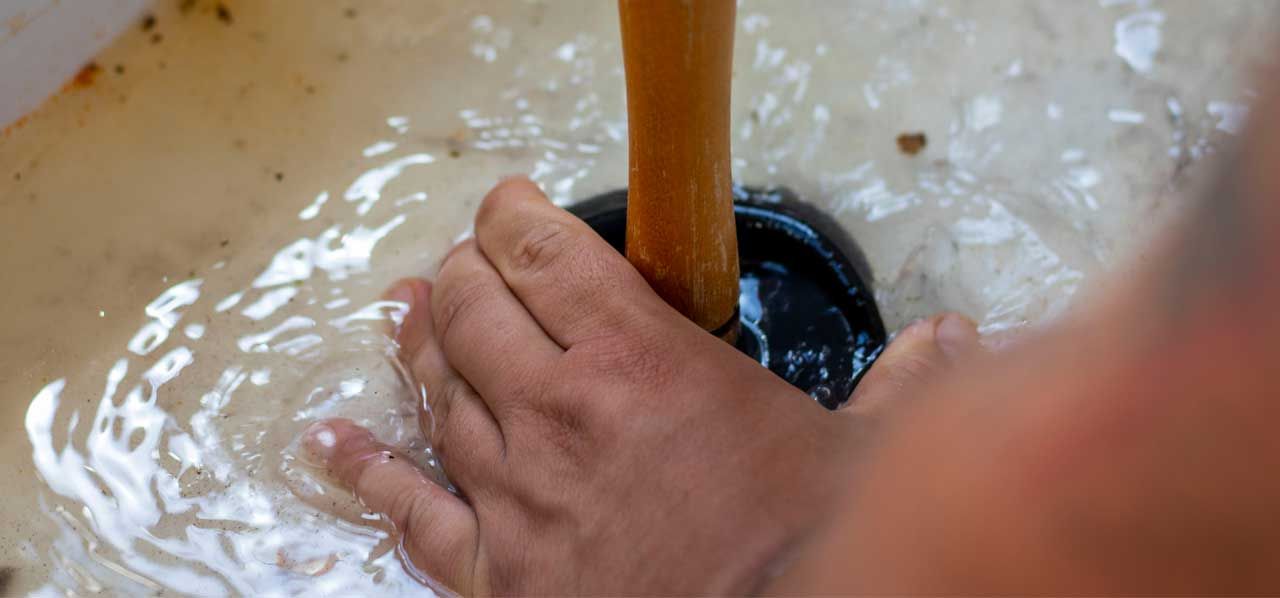 Hand stirring a pale batter or dough in a bowl with a wooden spoon