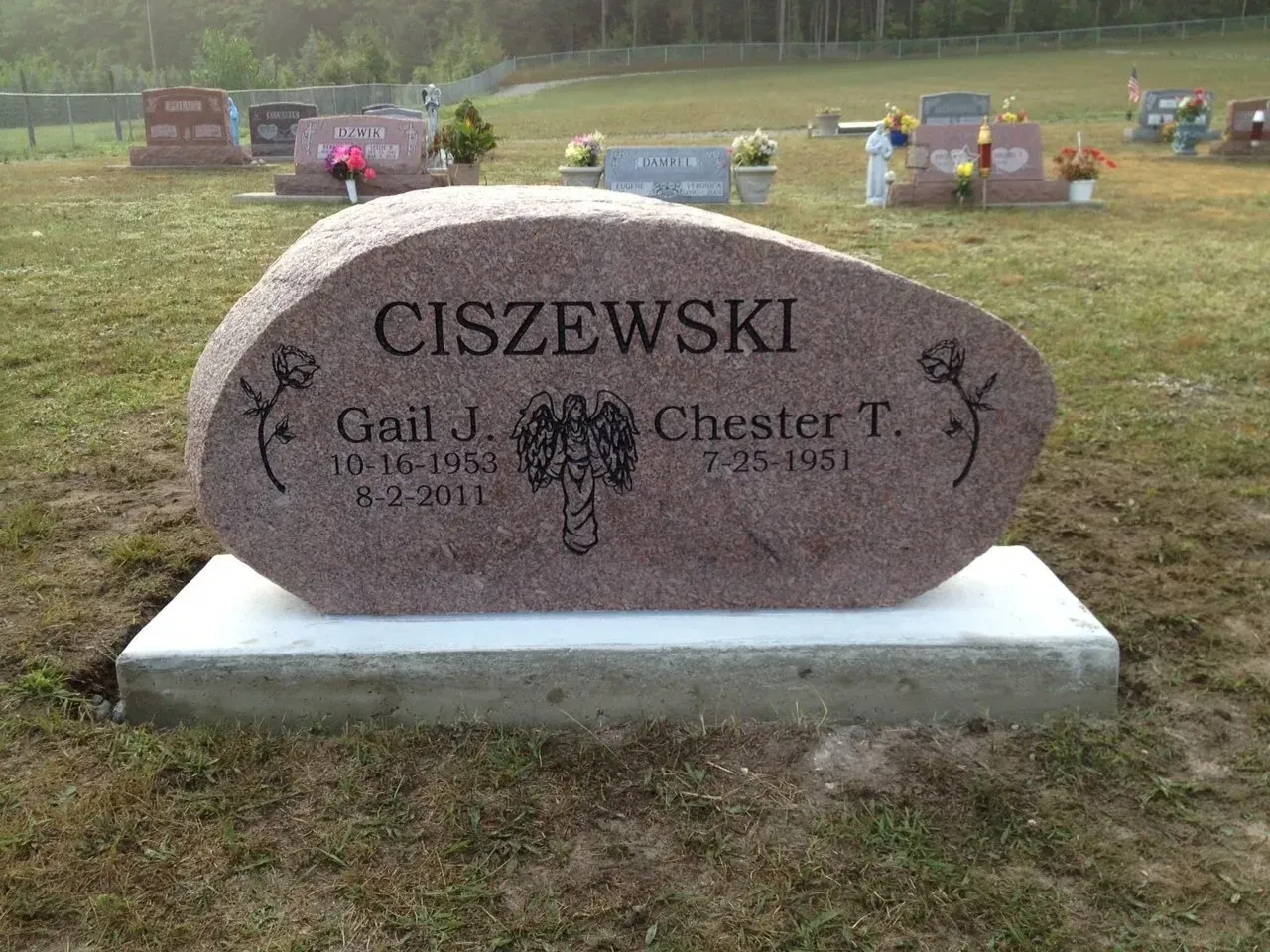 Gravestone of Gail J. and Chester T. Ciszewski. Stone is pink with names and dates. Located in a cemetery.