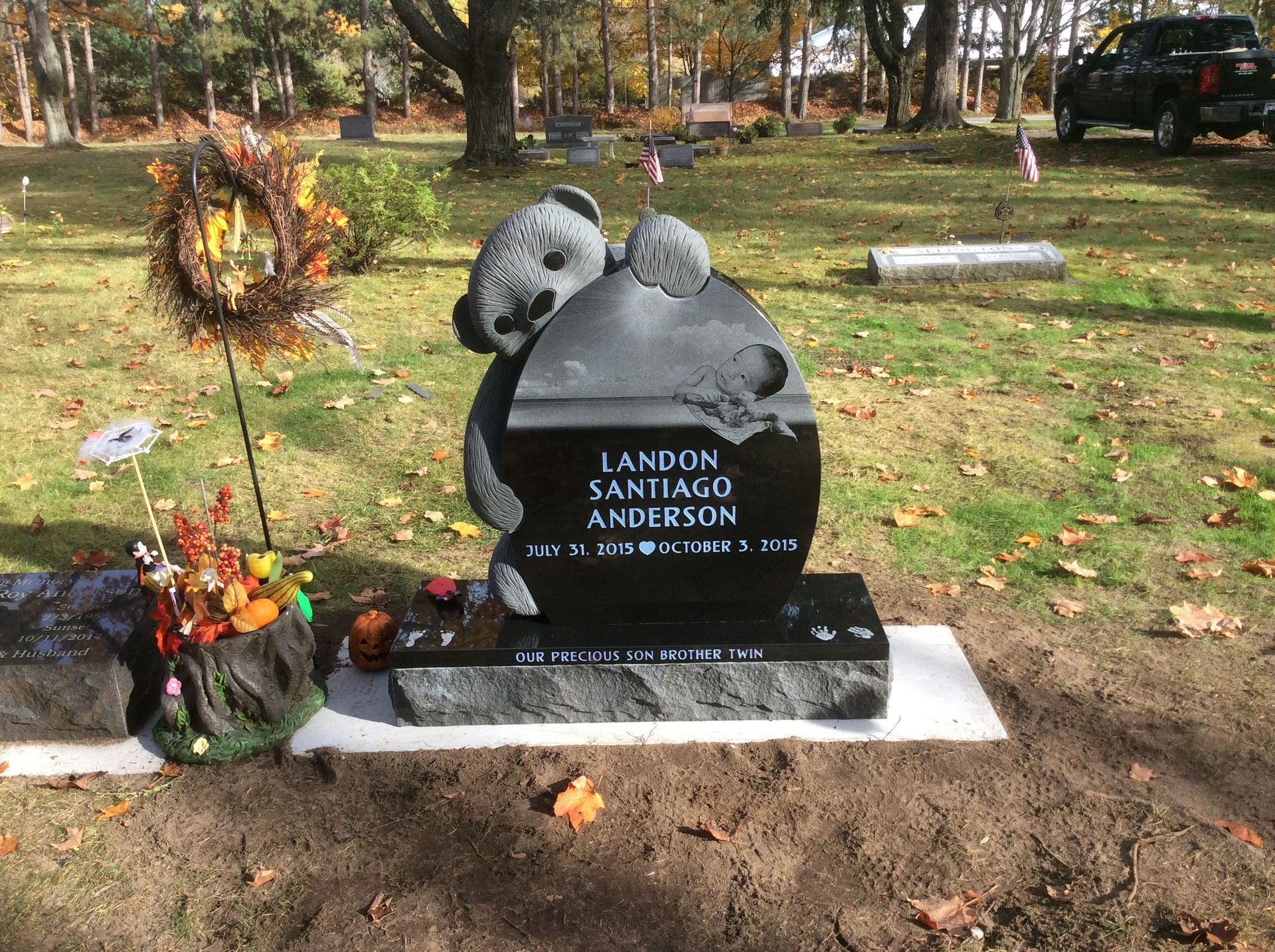 Gravestone with a teddy bear design in a cemetery.