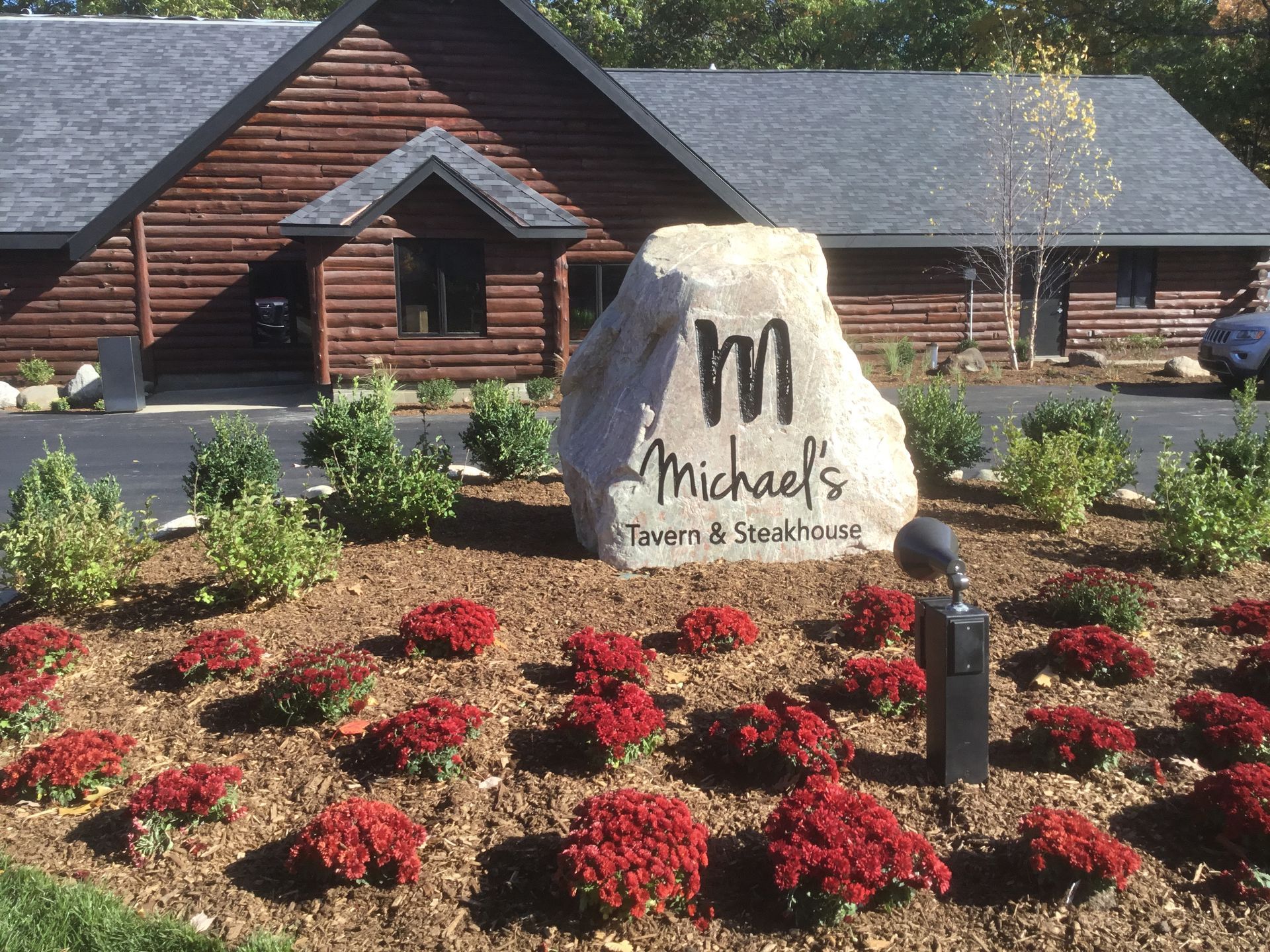 Michael's Restaurant sign in front of a log cabin building with red flowers.