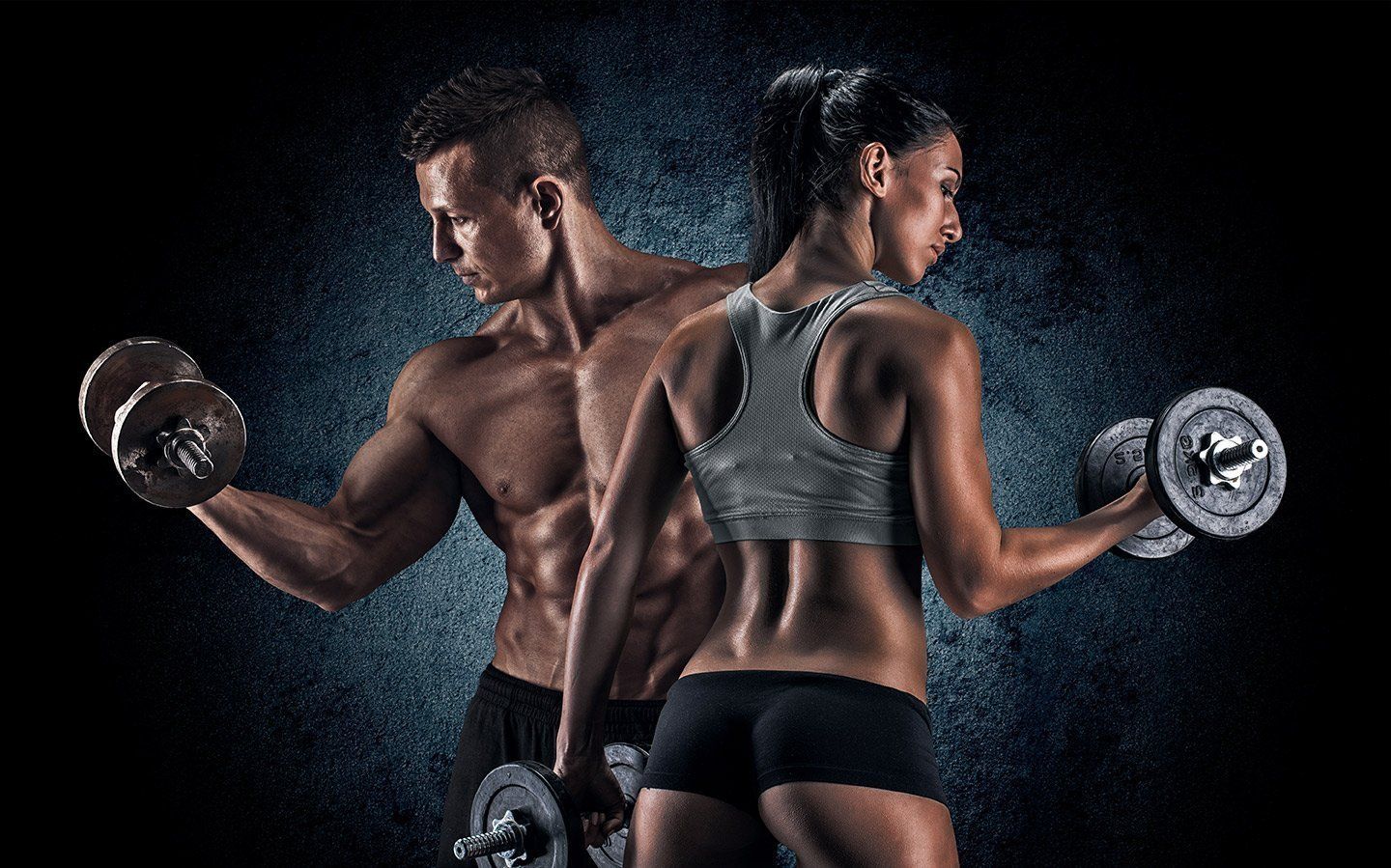 A man and woman with dumbbells, working out. They are muscular, against a dark blue background.