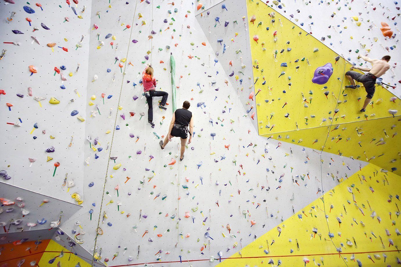 People climbing on a colorful indoor rock climbing wall.