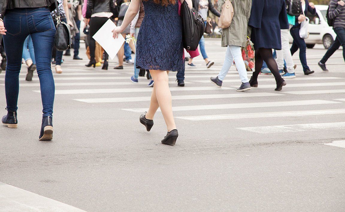 People walking across a crosswalk on a city street.