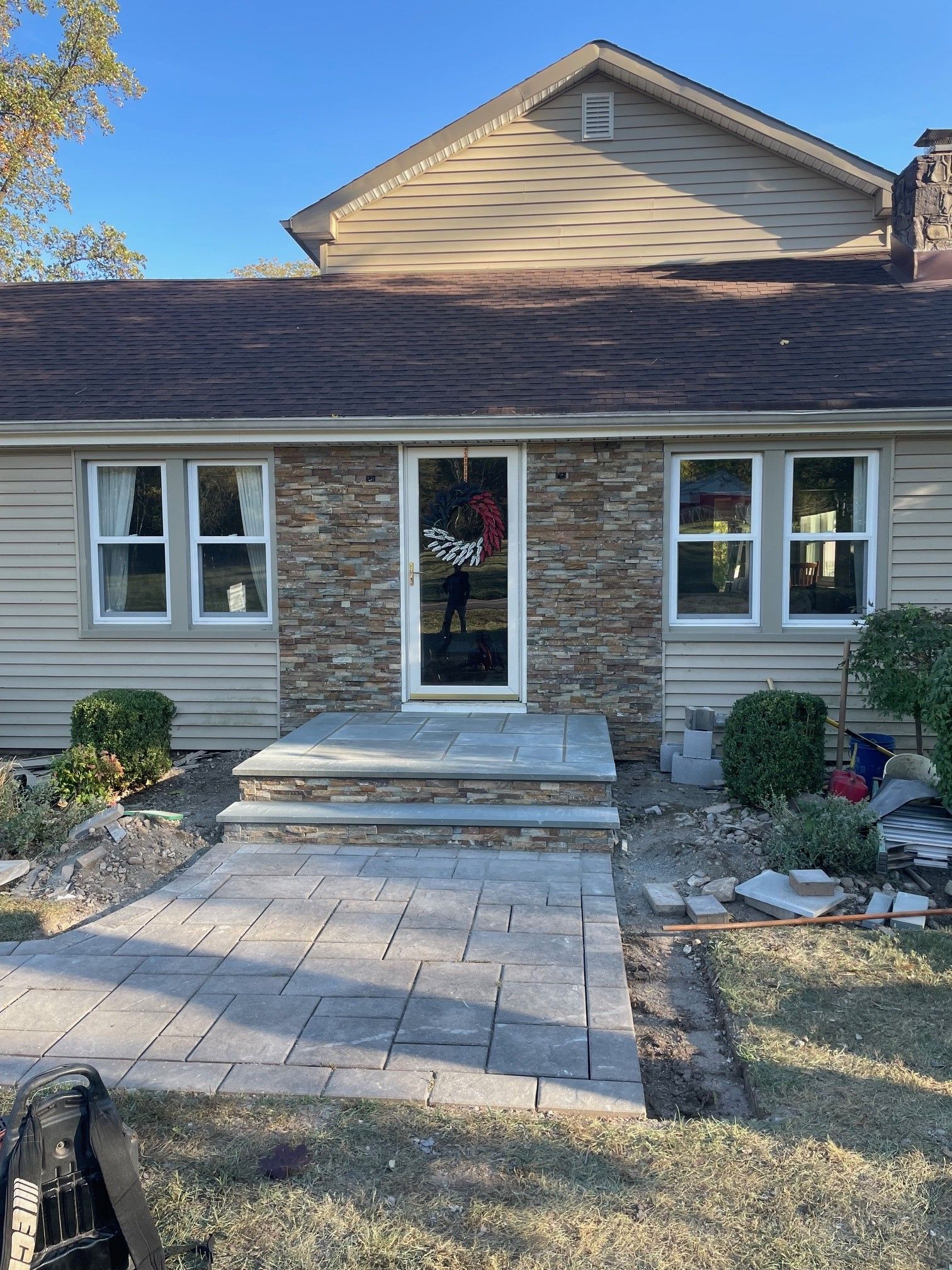A house with a stone wall and a walkway in front of it