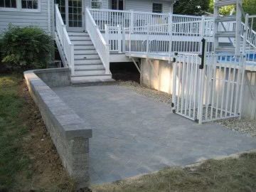 A concrete patio with white railing and steps