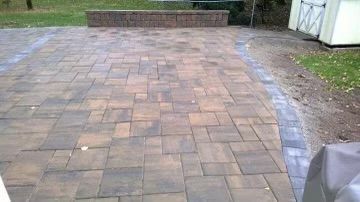 A cozy brick patio with a wall and a bench