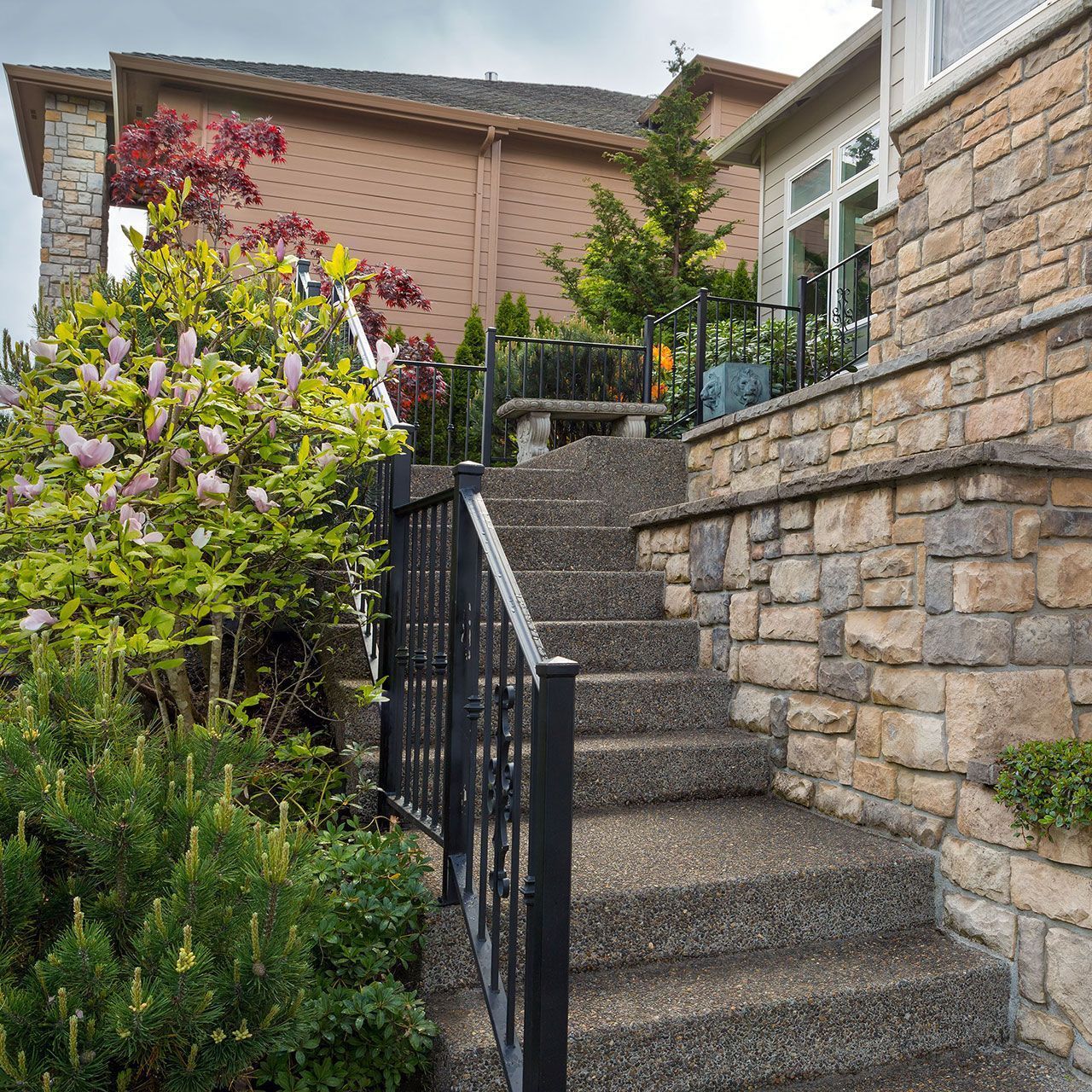 House front yard cultured veneer stone work siding and rod iron stairs.