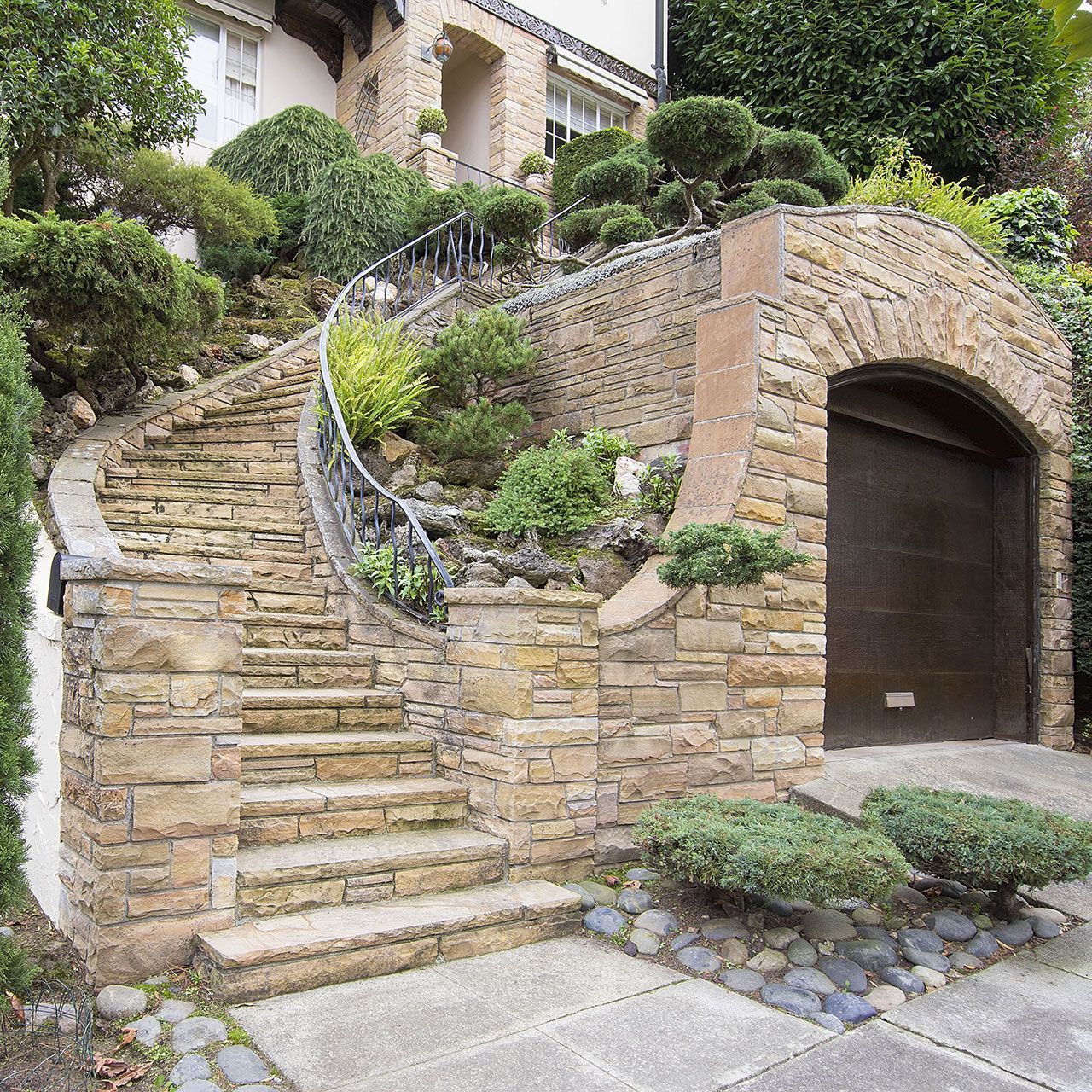 Stone veneer facade on home exterior with manicured front entrance yard landscape.