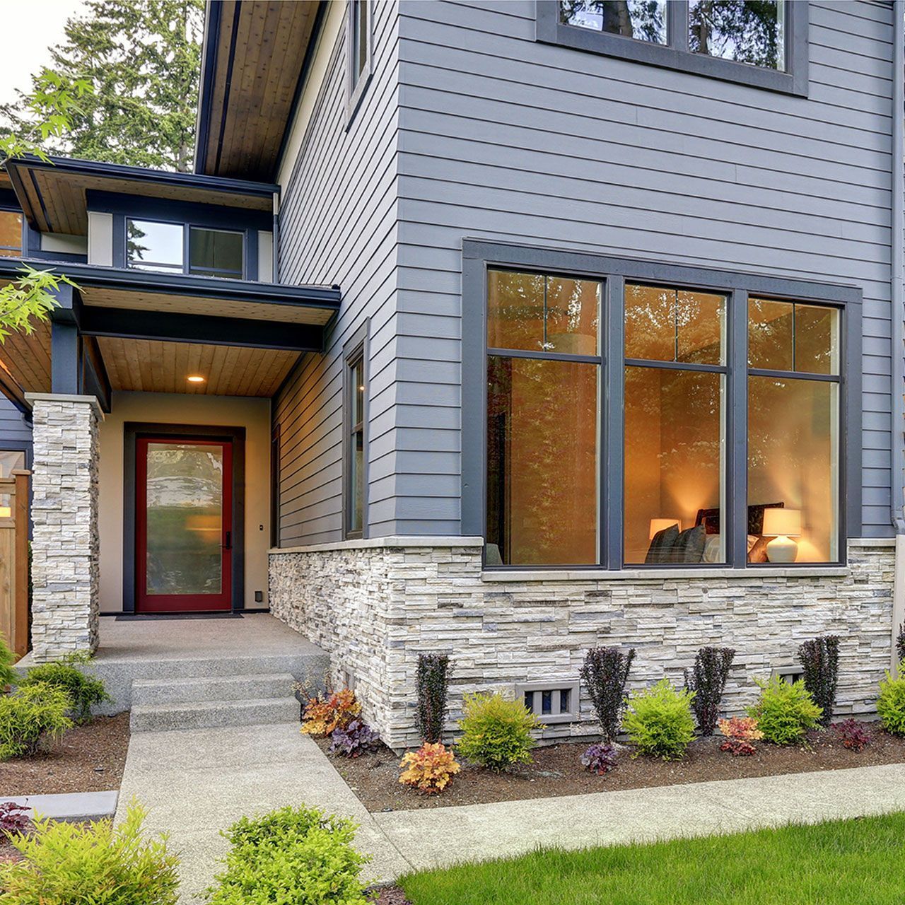 Stone foundation veneer, covered porch and concrete pathway.