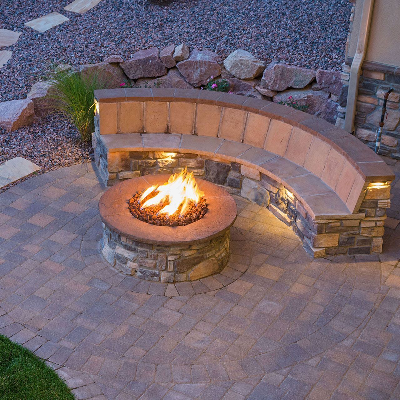 A stone veneer facing fire pit is surrounded by a curved stone bench.