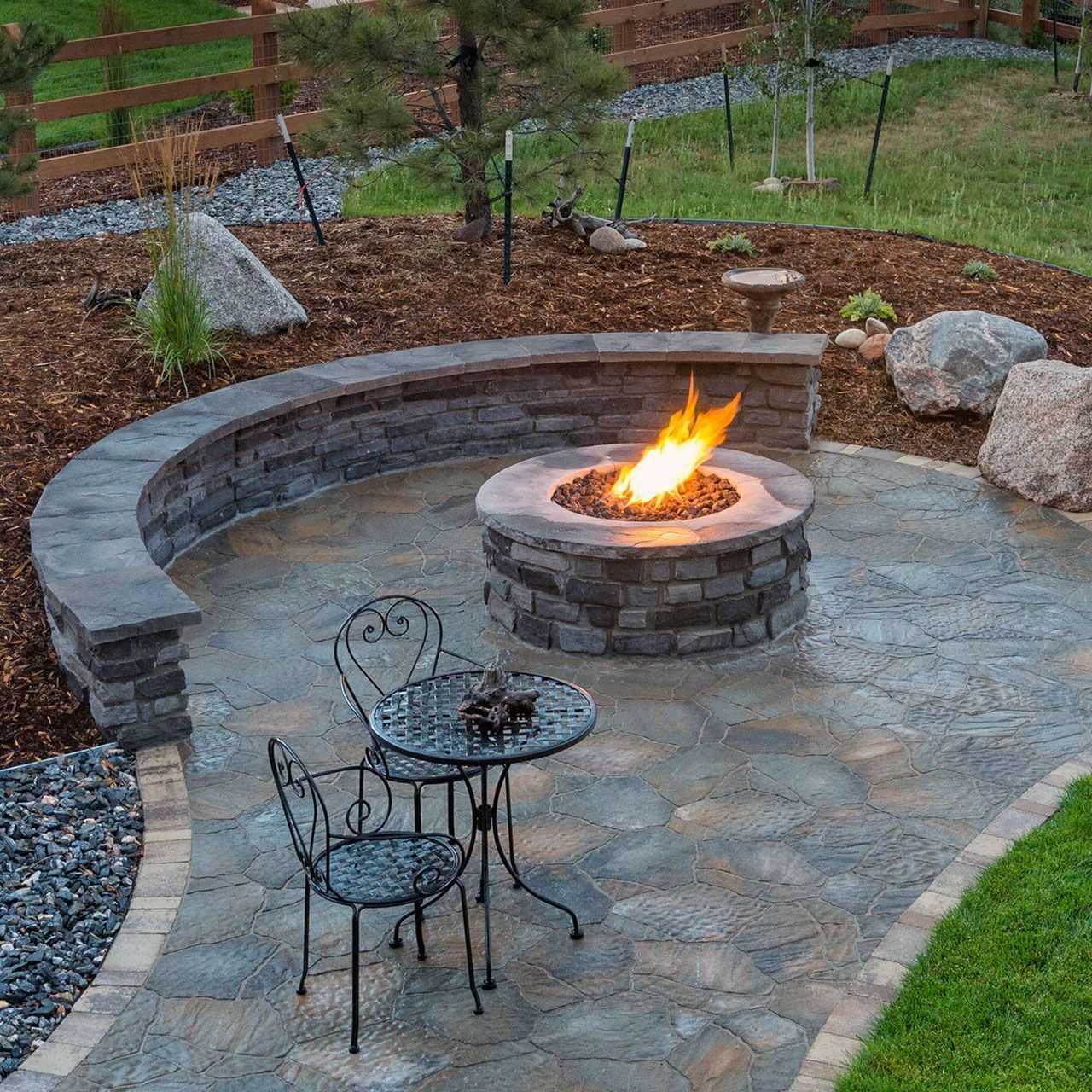 A stone veneer facing fire pit with a table and chairs around it.