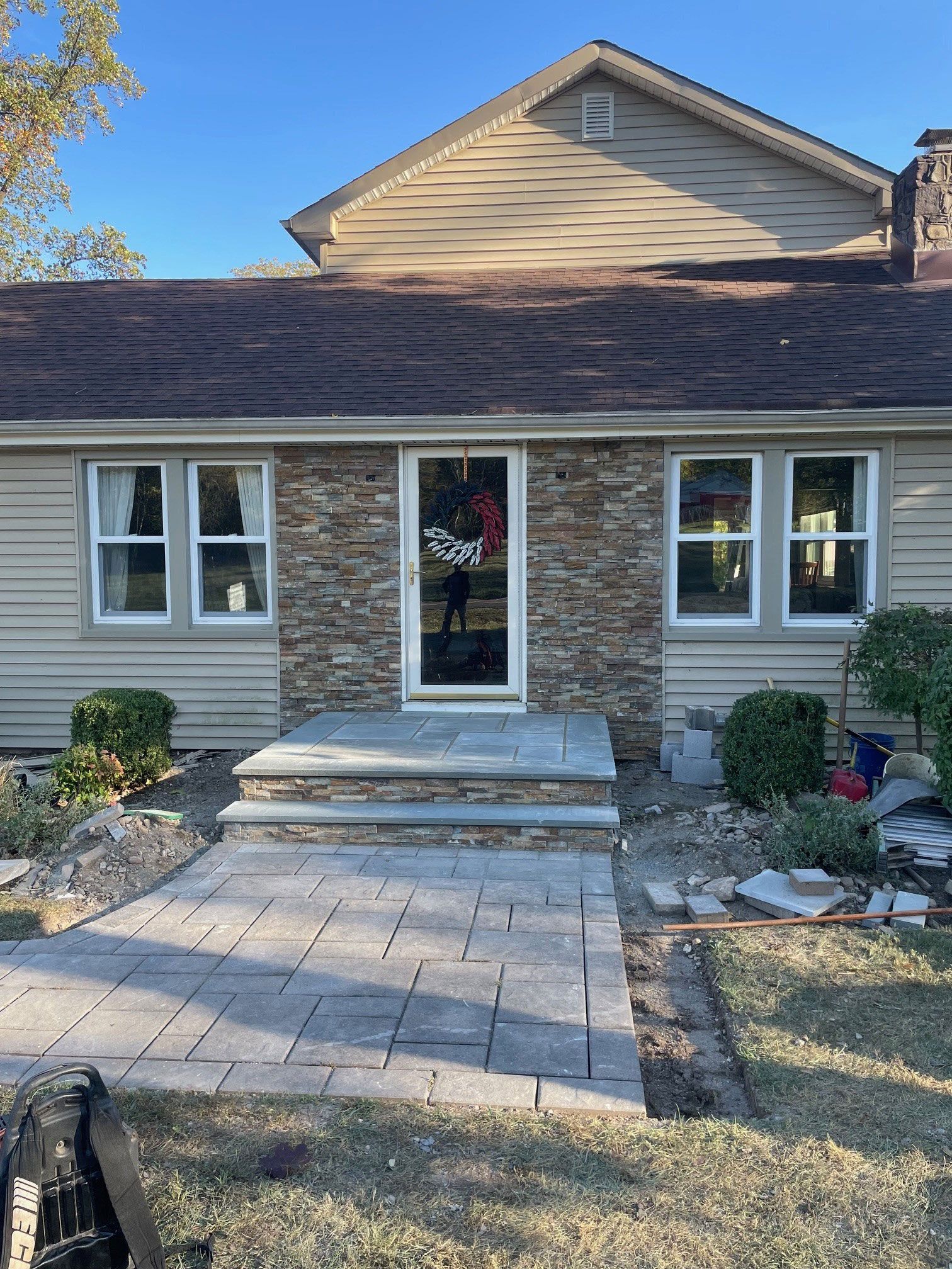 A house with a stone wall and a patio in front of it