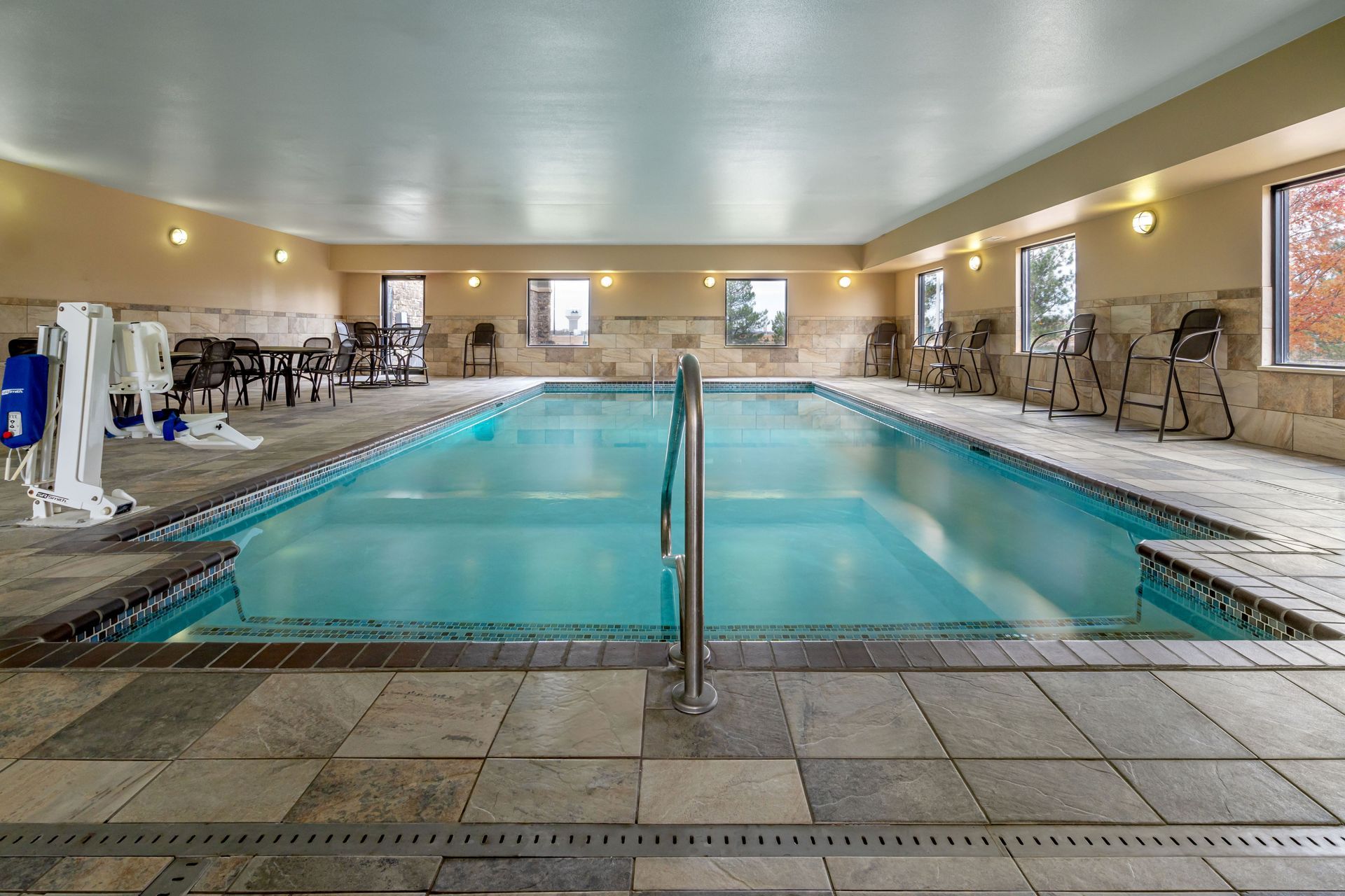 A large indoor swimming pool with chairs and a wheelchair.