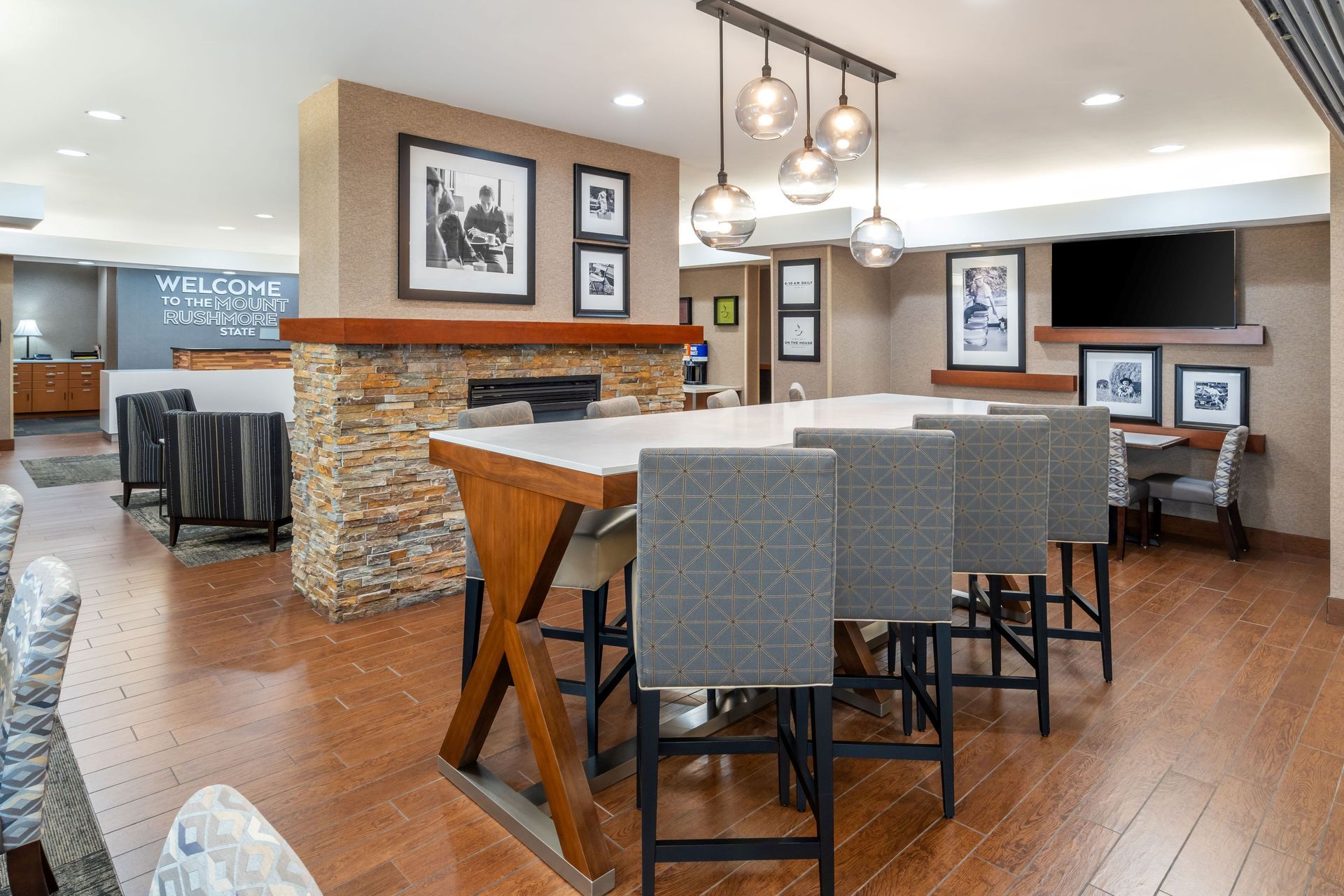 A hotel lobby with a long table and chairs and a fireplace.