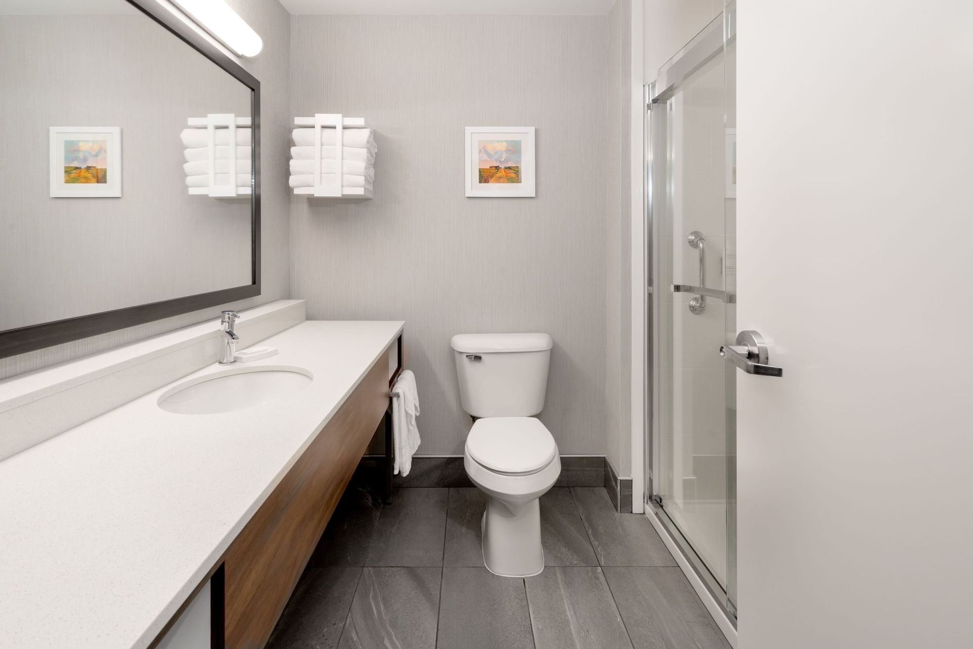 A bathroom with a toilet , sink , mirror and shower.