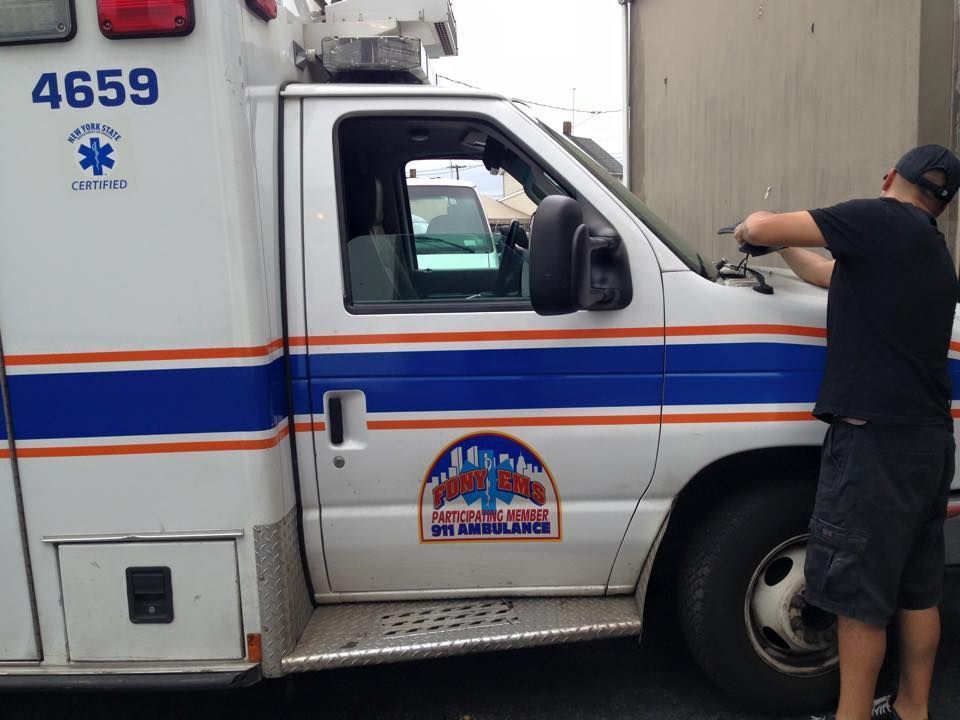 Ambulance side view with a man leaning on the front windshield in a parking lot