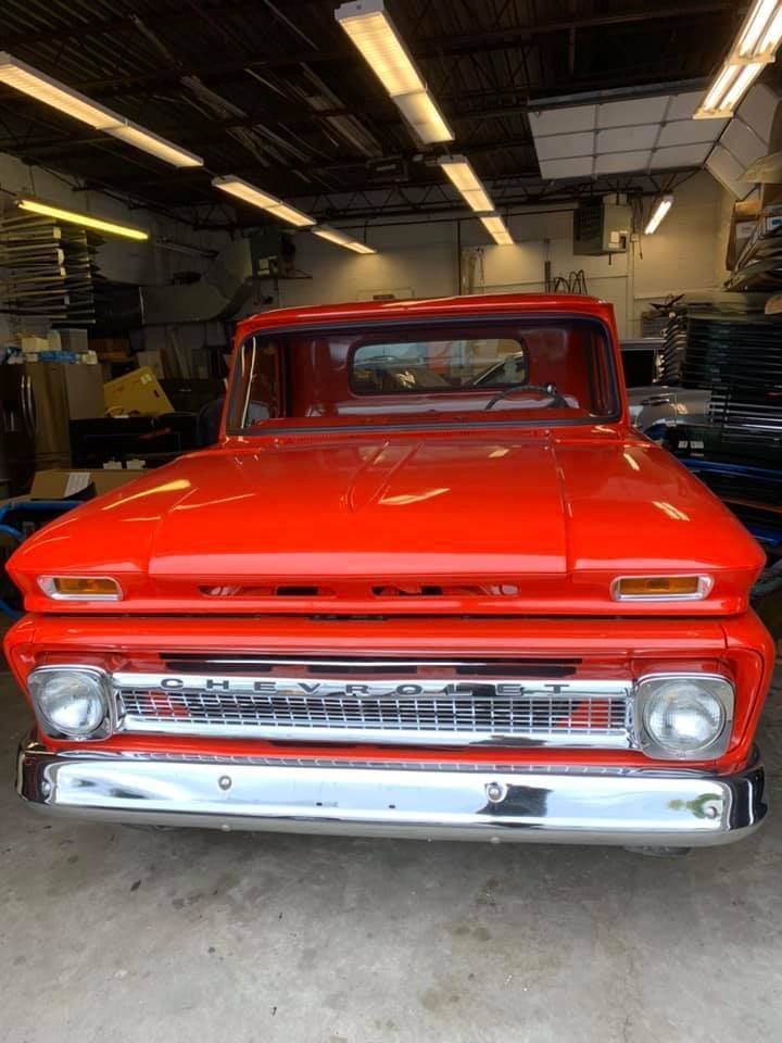 Bright red vintage pickup truck parked inside a garage, front view.