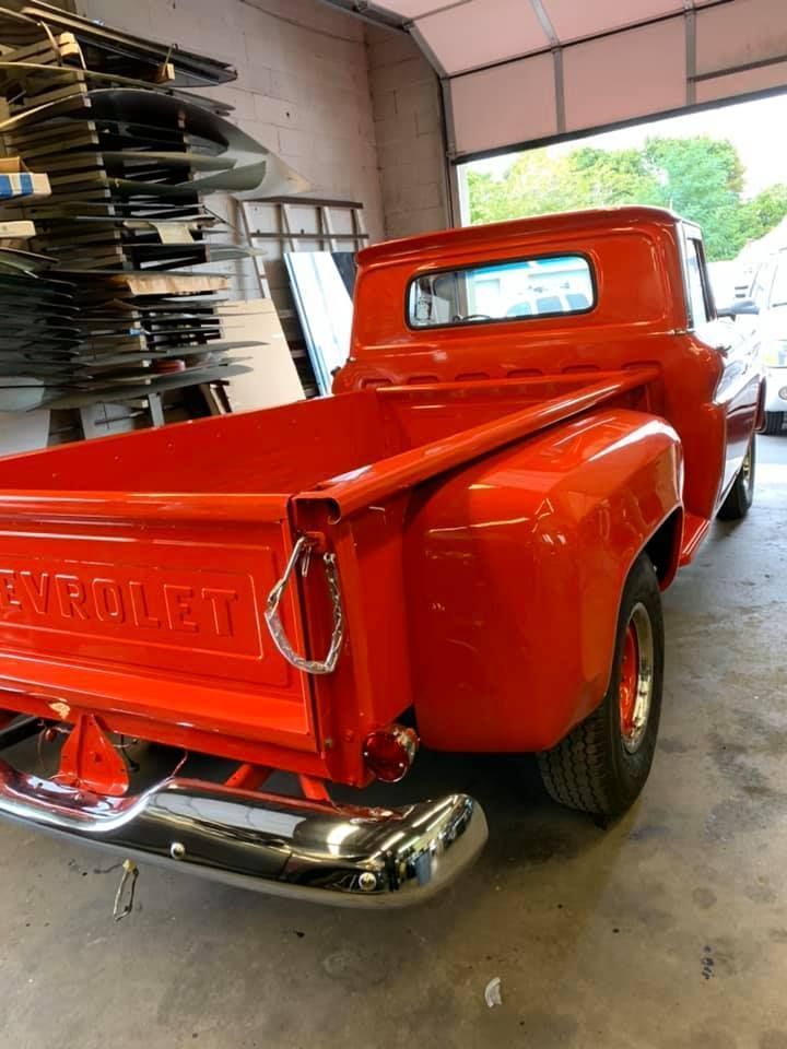 Bright orange classic Chevrolet pickup truck parked inside a garage