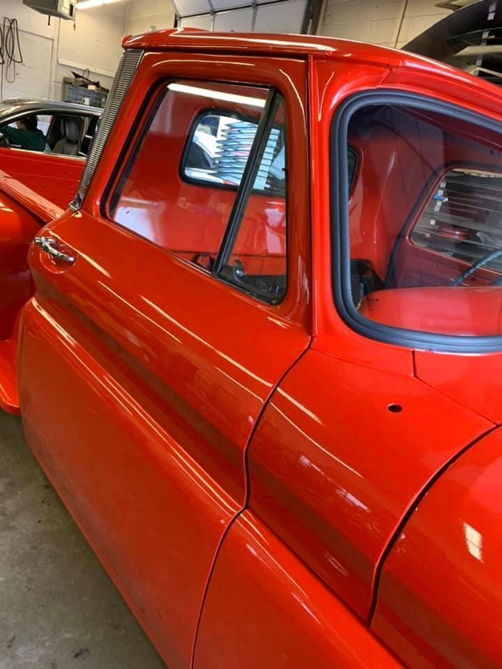 Bright red vintage car parked indoors, showing the side and rear window area