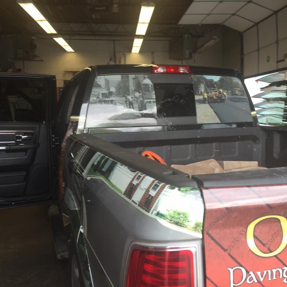 Silver pickup truck in a garage with an open tailgate and a red “Paving” sign on the rear.
