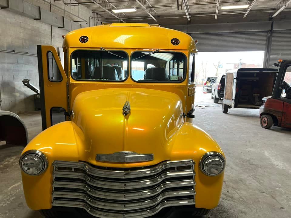Yellow vintage bus parked inside a garage, front view.