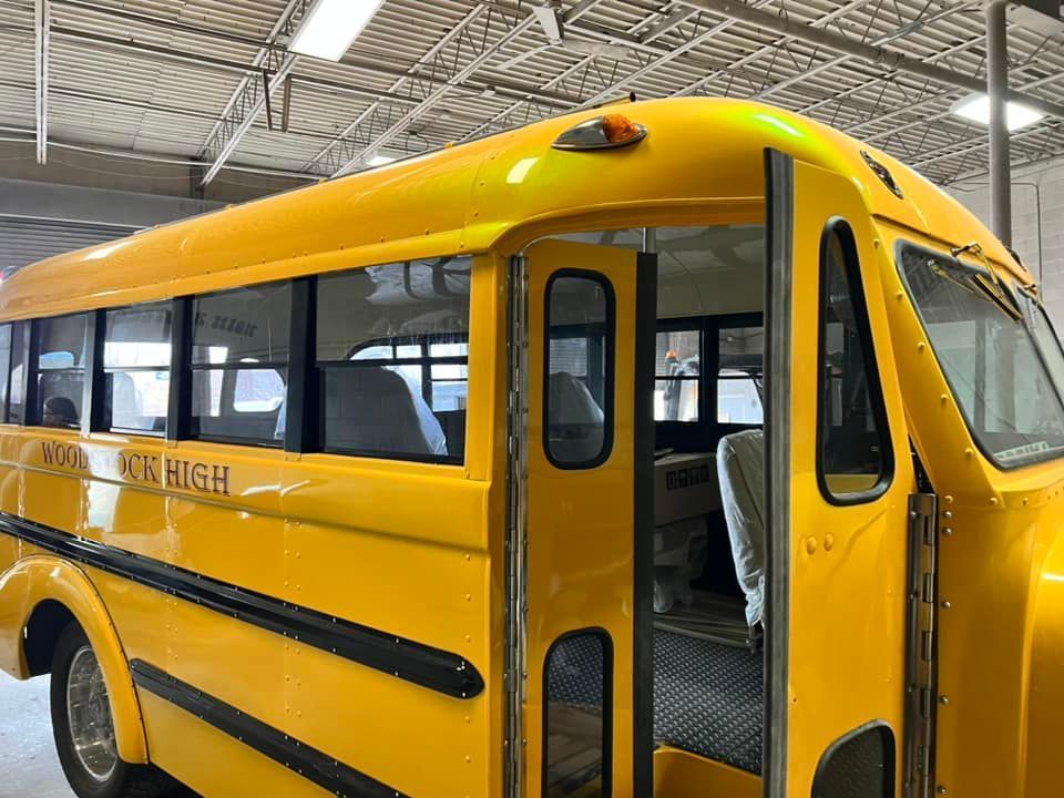 Yellow school bus parked indoors in a warehouse, showing its side and front doors.