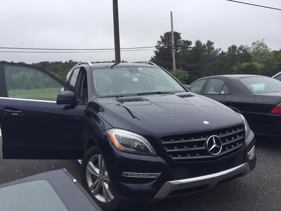 Dark blue Mercedes SUV with driver door open in a parking lot on an overcast day