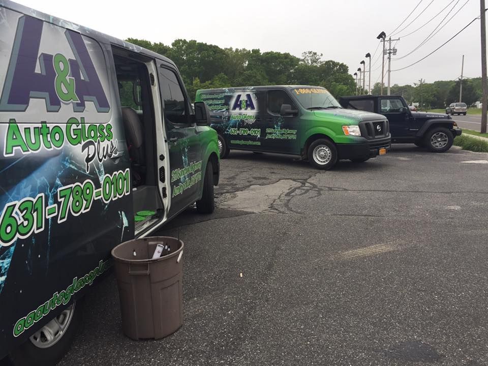 Auto detailing vans parked in a lot, with green-and-black branding and a trash bin in the foreground.