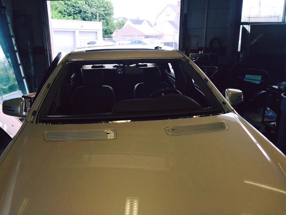White car parked inside a dim garage with another vehicle visible beside it