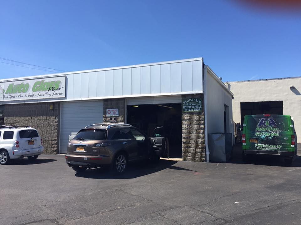 Auto shop exterior with parked vehicles, including a black SUV and a green van, under a clear blue sky