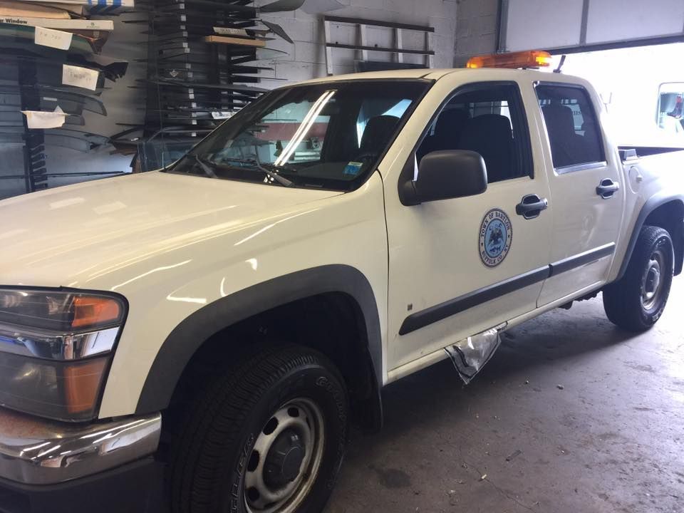 White utility pickup truck parked in a garage, with city/emergency-style markings on the door.