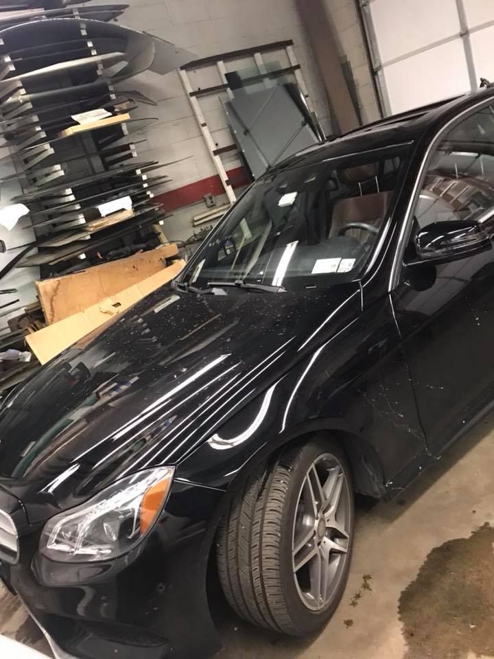 Black sports sedan with a damaged front wheel parked inside a garage workshop