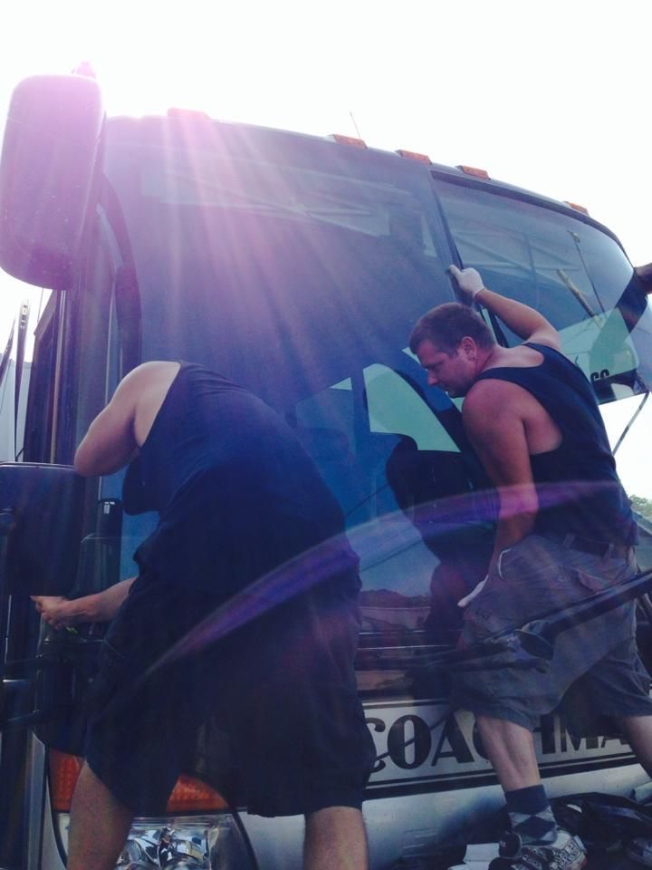 Two people loading items into a blue truck in bright sunlight