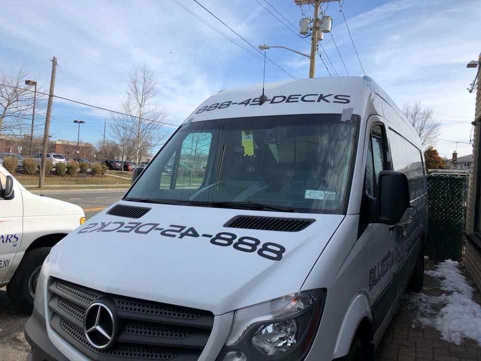 White Mercedes work van parked outdoors with “AQUA DECKS” branding and phone number on the windshield.