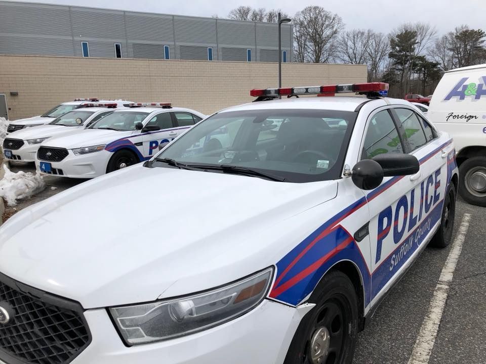 Police cars parked outside a building, with a white and blue patrol car in the foreground.
