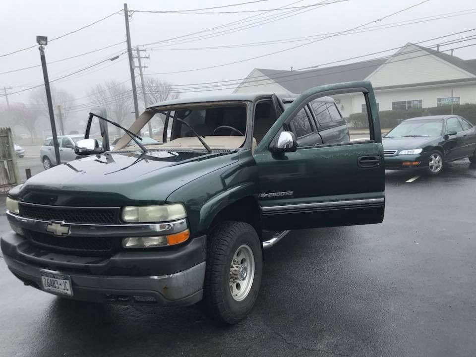Green Chevrolet pickup with open passenger door on a foggy street, windshield visibly damaged