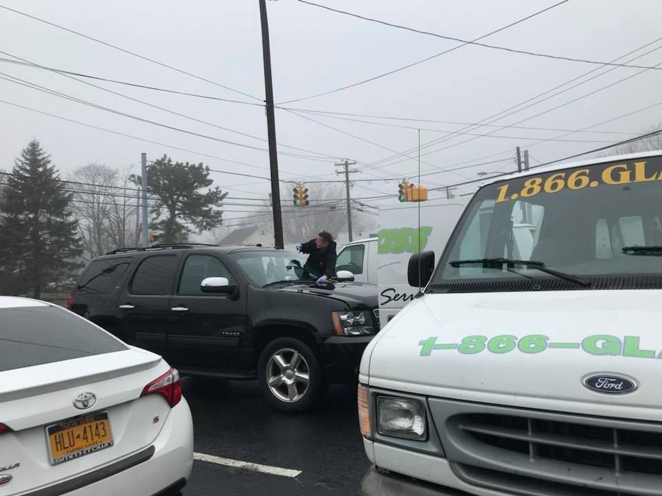 Tow truck and SUV in a foggy parking lot, with white sedan partially visible in foreground.
