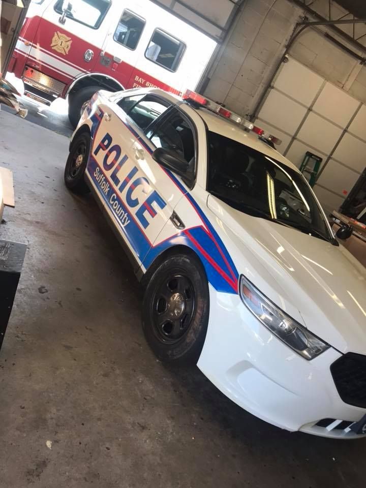 Police car parked in a garage beside a fire truck, viewed at an angle.