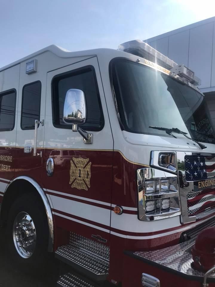 Red and white fire truck parked outside a building, shown from the front side.