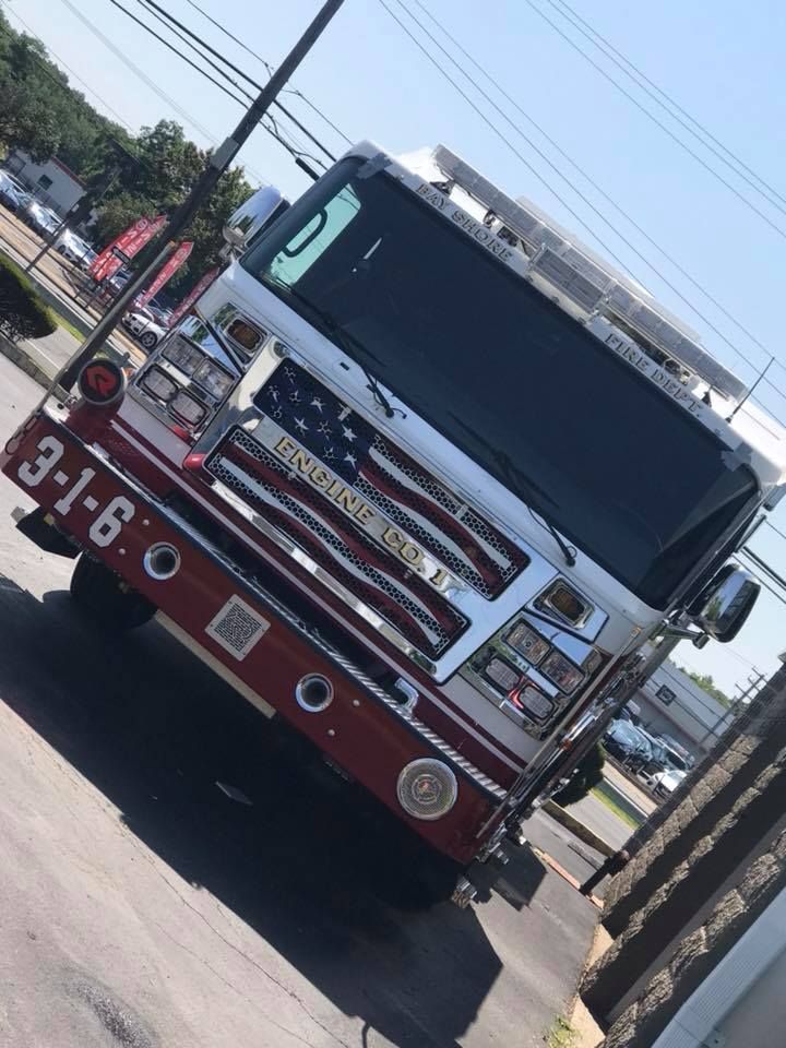 Red fire truck driving on a sunny street, front view angled toward the camera.