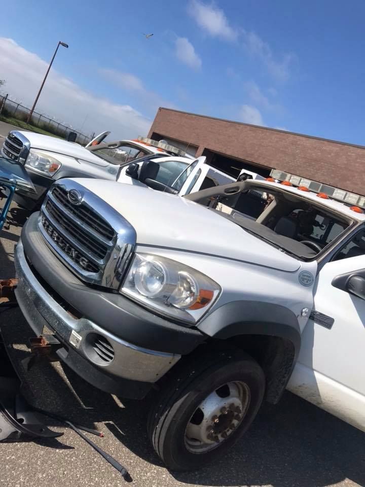 White pickup trucks parked in a lot beside a brick building on a sunny day
