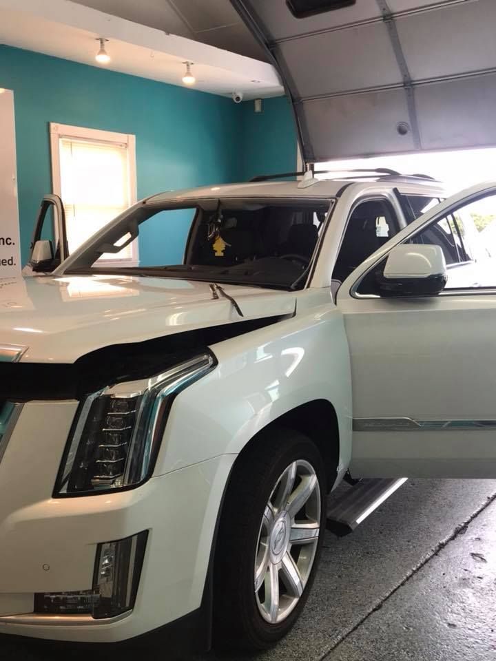 White SUV in a garage with the driver’s door open and the hood raised